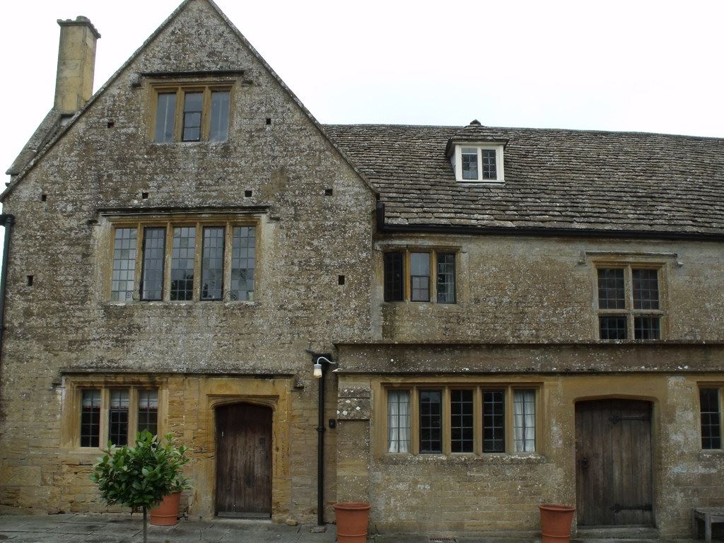 A honey-coloured Cotswold stone house with mullioned windows and a heavy timber door